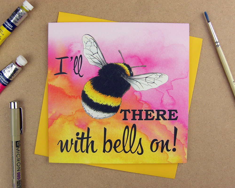 Greetings card with the words 'I'll be there with bells on' with the word 'be' replaced with an illustrated bumblebee on pink watercolour background